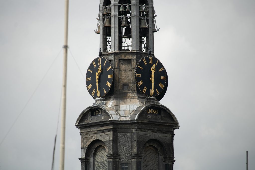 Close-up of the Munttoren clock tower in Amsterdam with cloudy sky background.